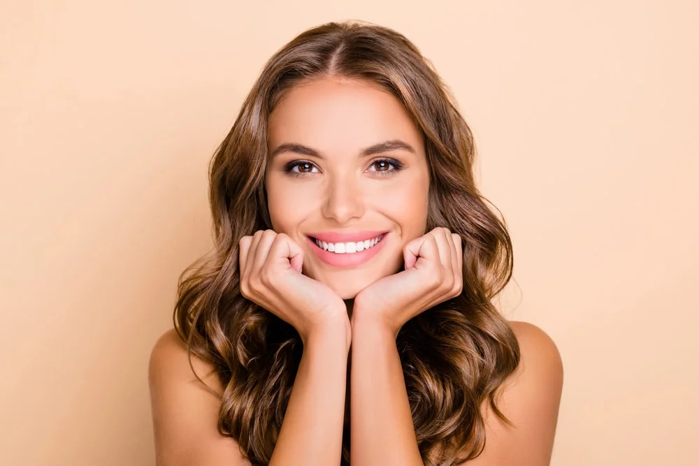 Model smiling, with her hands propped up under her cheeks