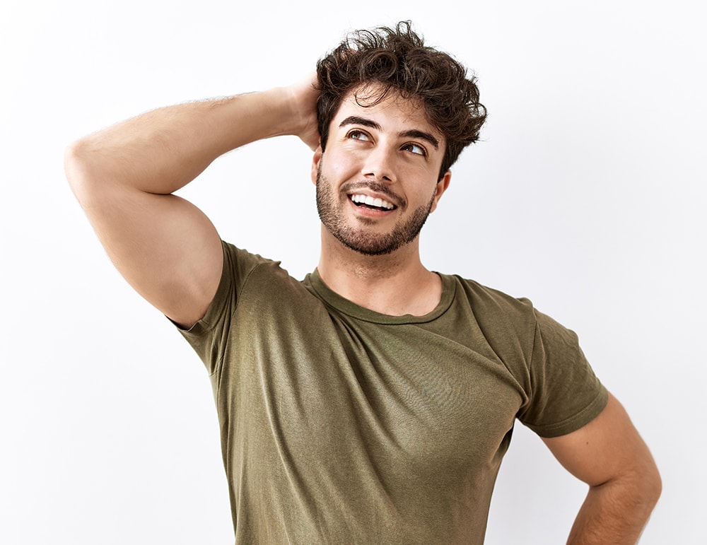 Hispanic man standing over isolated white background smiling confident touching hair with hand up gesture, posing attractive and fashionable