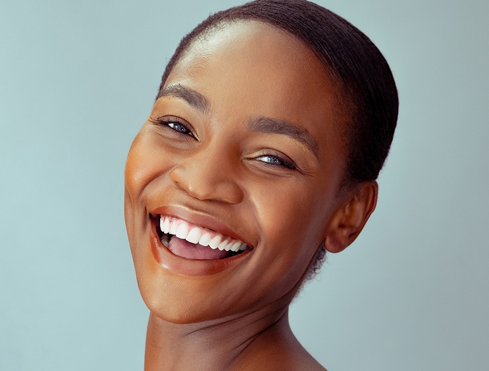 Happy beauty african woman looking at camera isolated on background with copy space. Cheerful mid woman smiling after skin treatment. Beautiful middle aged lady having fun after beauty therapy.