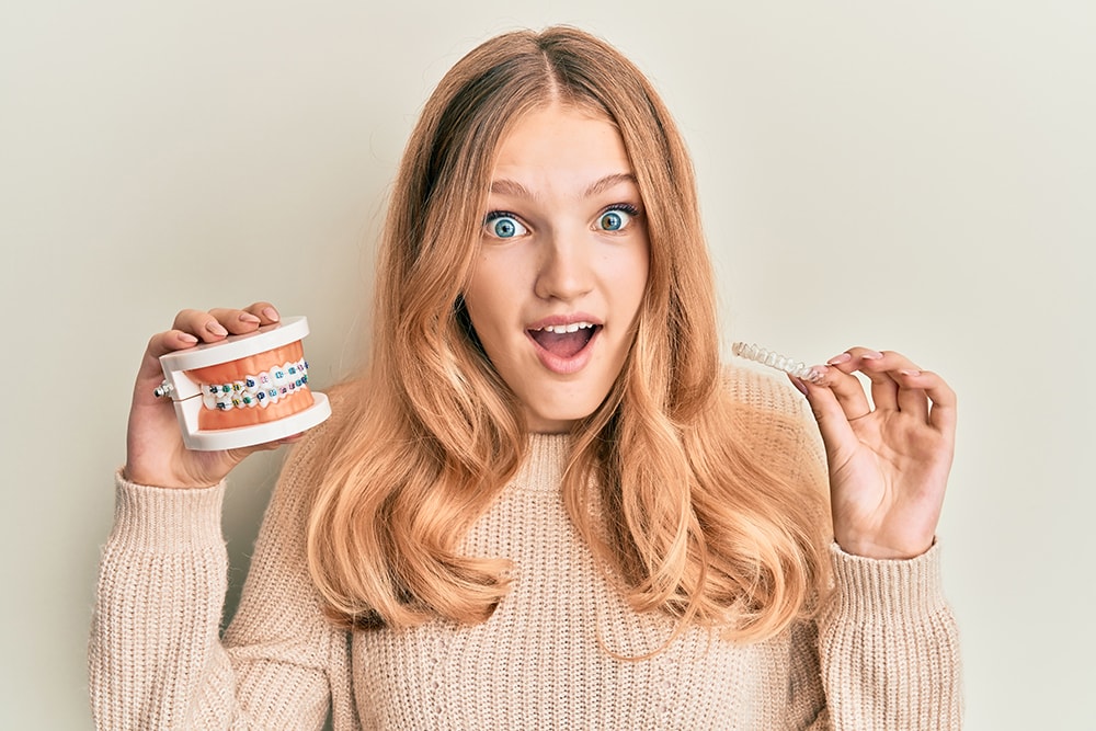 Beautiful young caucasian girl holding invisible aligner orthodontic and braces celebrating crazy and amazed for success with open eyes screaming excited.