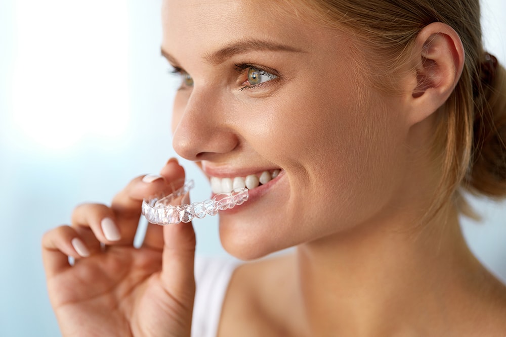 Orthodontics. Closeup Of Beautiful Happy Smiling Woman With White Smile, Straight Teeth Holding Whitening Tray, Invisible Braces, Teeth Trainer. Dental Treatment, Health Concept.